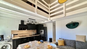 A modern kitchen with black cabinets, a wooden countertop, and a dining area with a table set for four. - 3-room apartment with pool, AC and Wi-Fi in Porticcio (Porticcio)