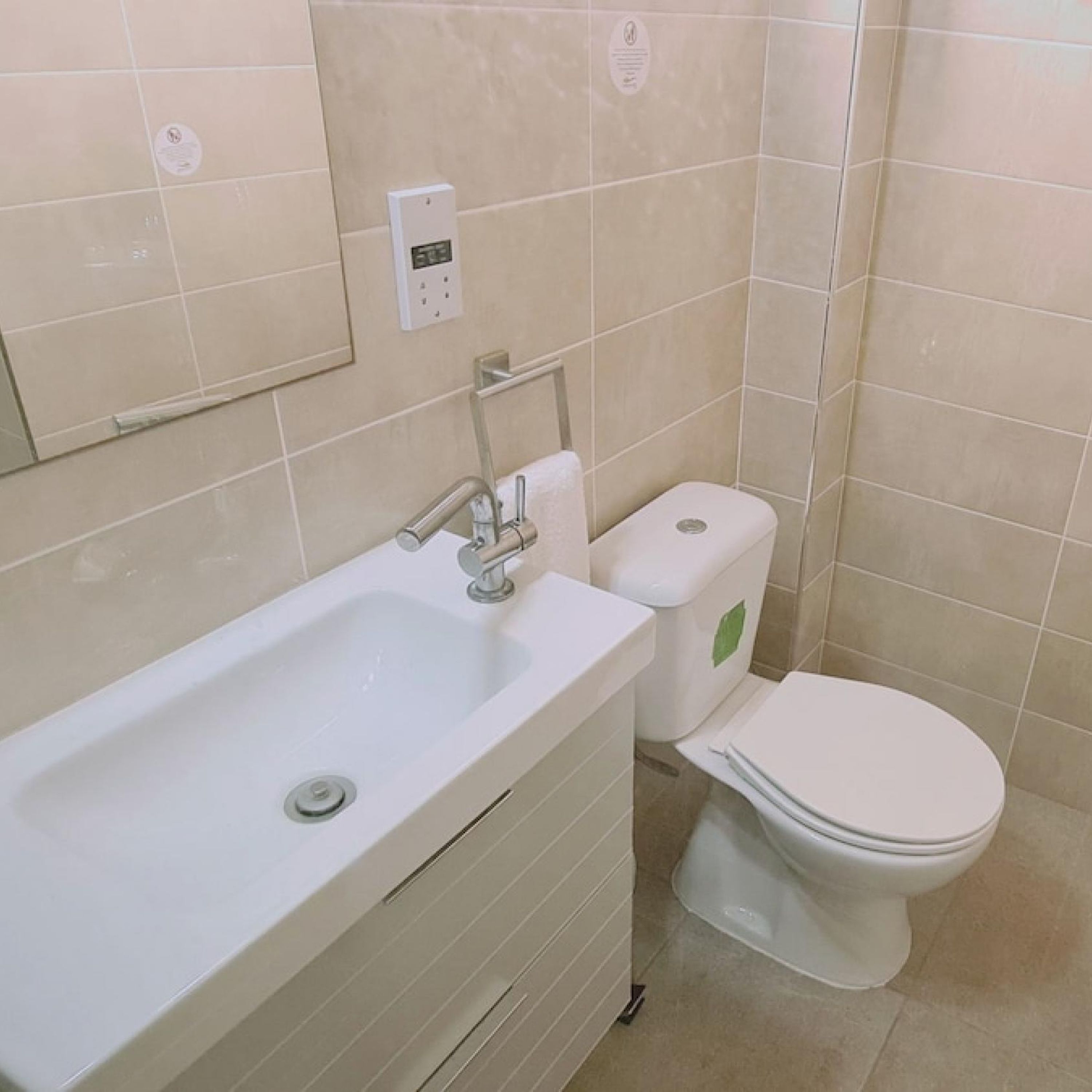 Un baño con lavamanos blanco, inodoro y espejo en la pared.