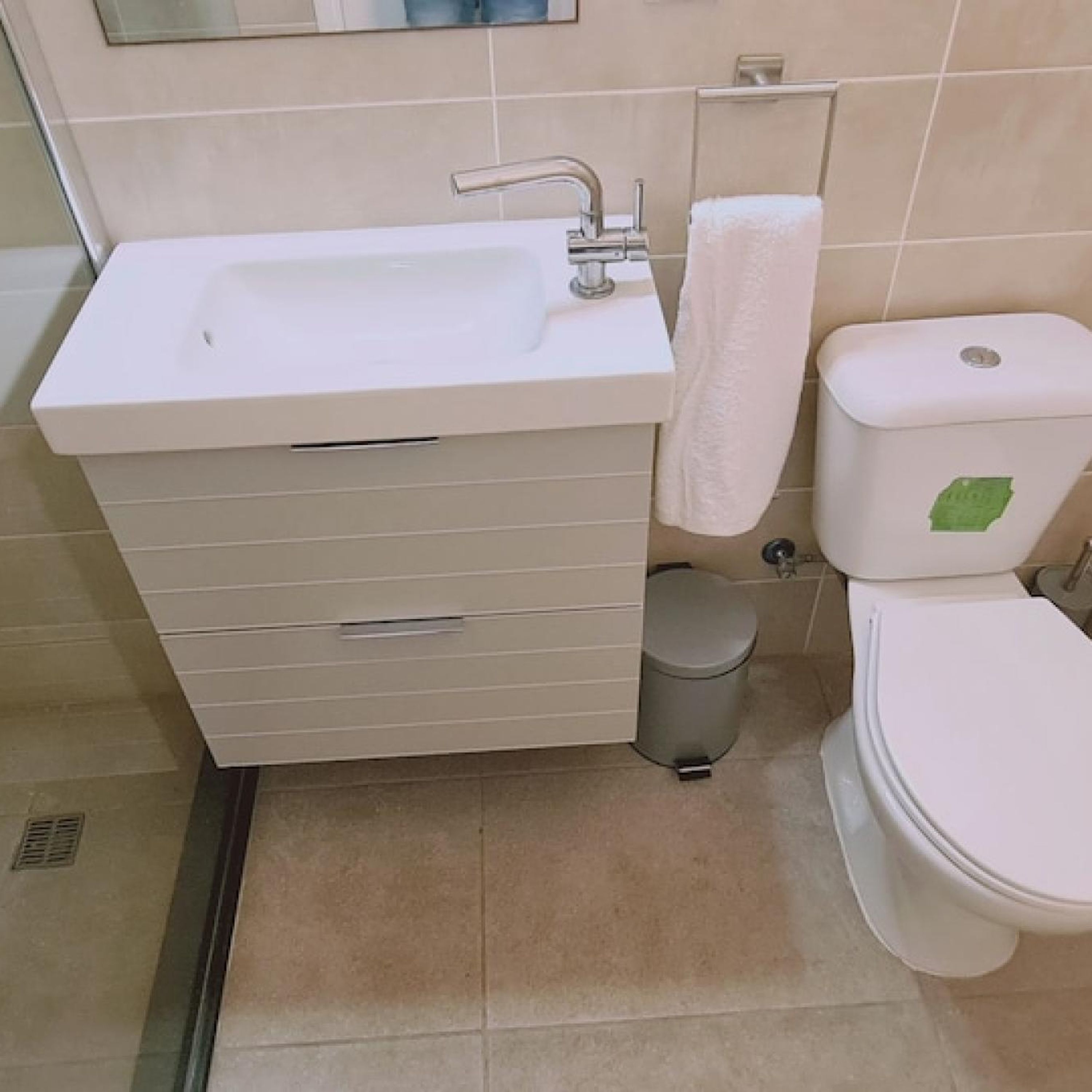 Un baño con lavamanos blanco, inodoro y cubo de basura.