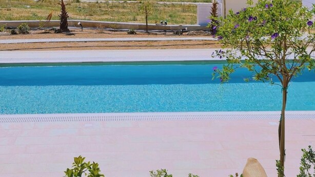 Une piscine offrant une vue sur un quartier résidentiel et, au loin, sur la mer.
