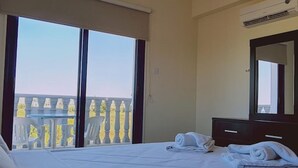 A hotel room with a bed, a dresser, a mirror, and a window with a view of a building. - 20 ATR -trinity 1 Apartment (Paralimni)