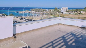 A balcony with a view of a beach and parking area. - 20 ATR -trinity 1 Apartment (Paralimni)