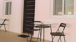 A room with a tiled floor, a round table with chairs, a black door, and a window.