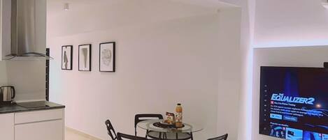A modern living space with a kitchen, dining area, and a TV mounted on the wall.