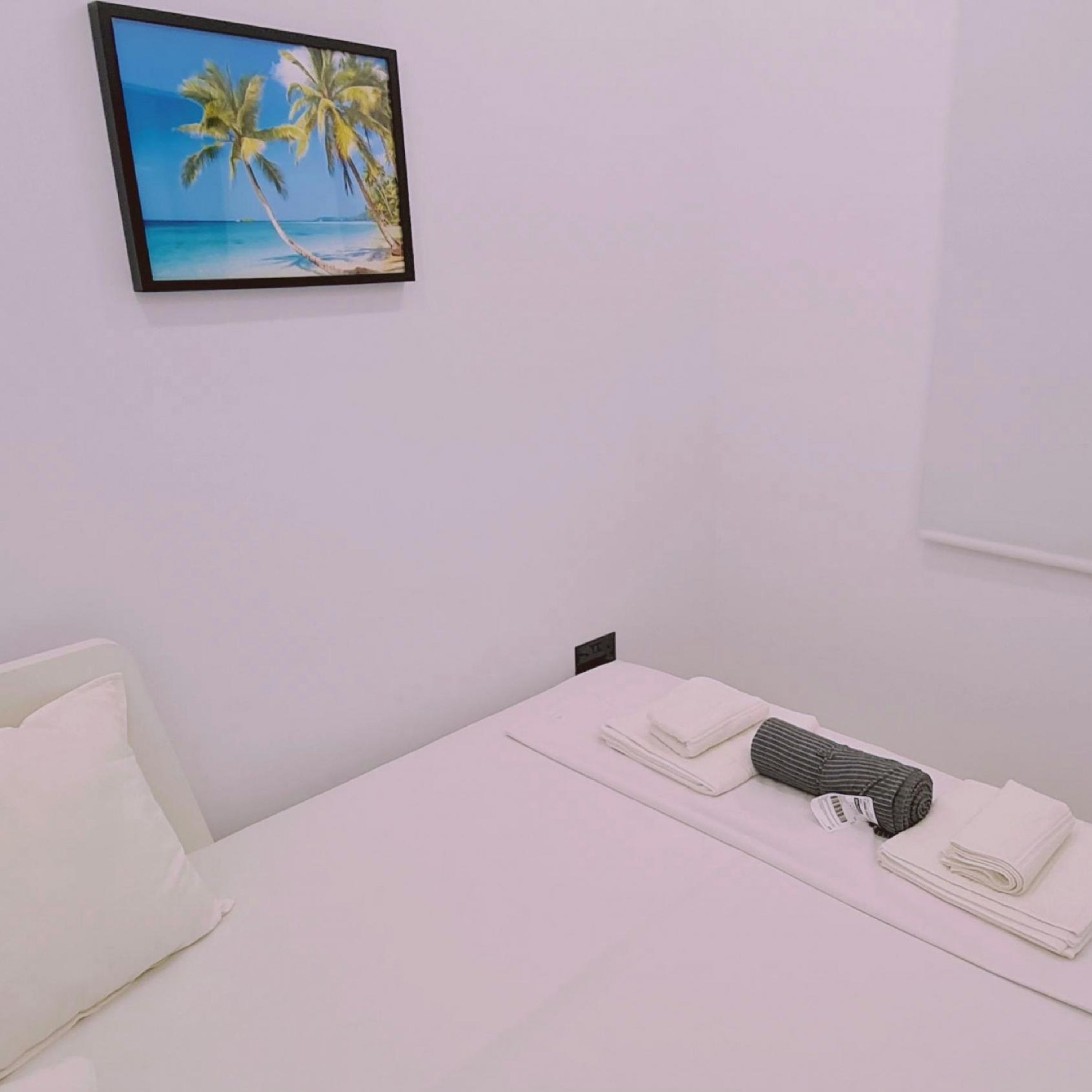 A hotel room with a bed, a pillow, a folded towel, and a striped pillow.