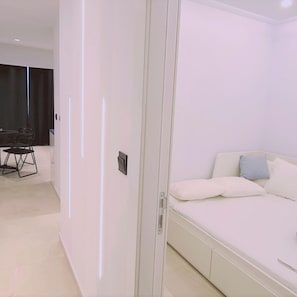 Un dormitorio moderno con cama, mesita de noche y un pequeño escritorio con silla.