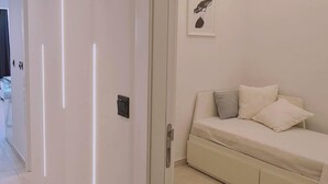 A modern bedroom with a bed, a bedside table, and a wall-mounted light fixture.