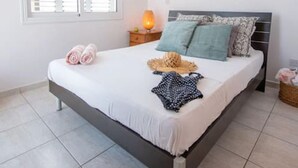 Ein Schlafzimmer mit Bett, einem Fenster mit Jalousien, einer Wand-Klimaanlage, einer Nachttischlampe und einem Schild mit der Aufschrift 'LOVE'.