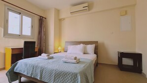 A neatly arranged hotel room with a bed, a desk, and an air conditioning unit. - 40 PRO 2 - Sunrise Beach Apt 2 (Paralimni)