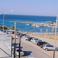 Un estacionamiento con coches y vistas al mar y la playa.