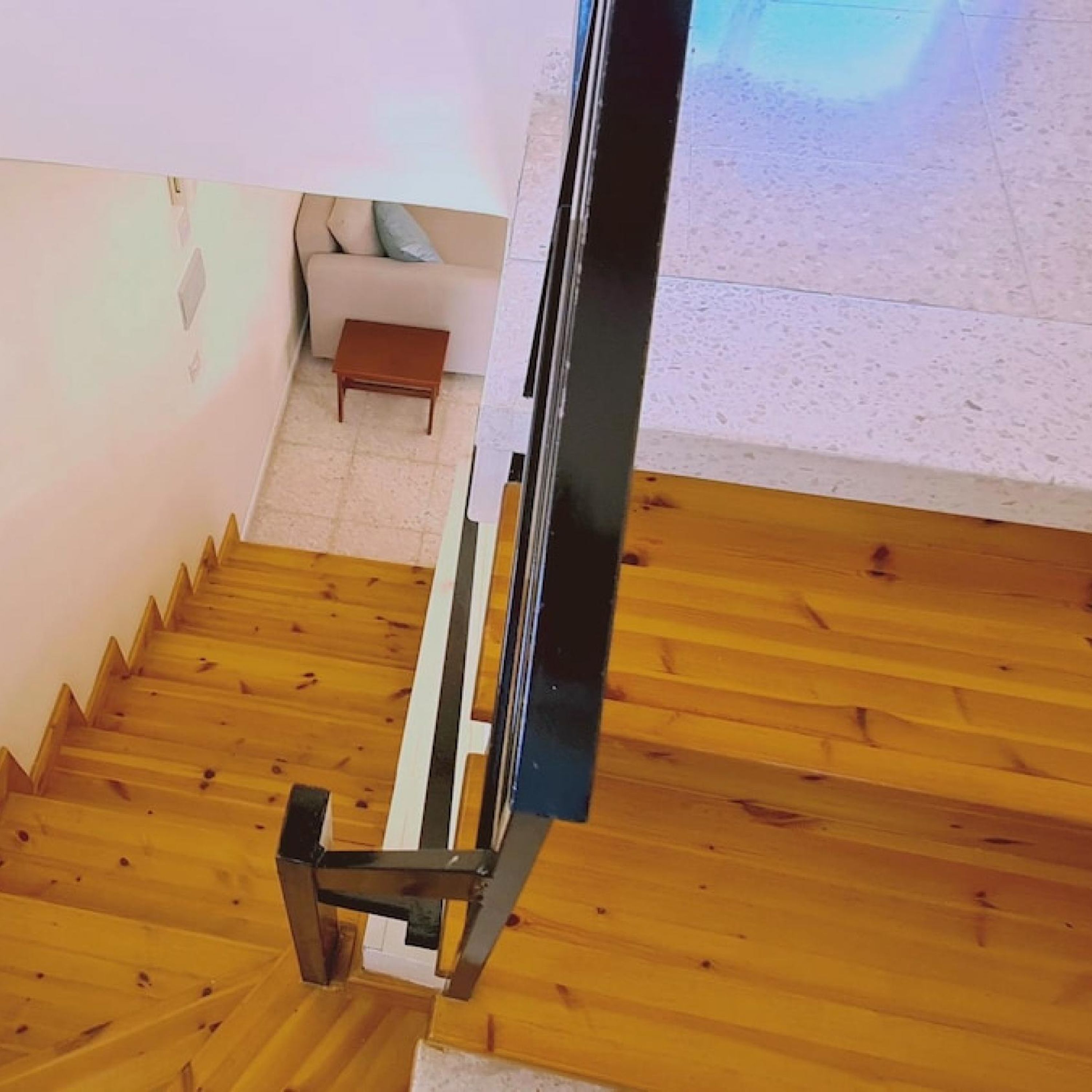 Een houten trap met een metalen leuning die uitkomt op een plateau.