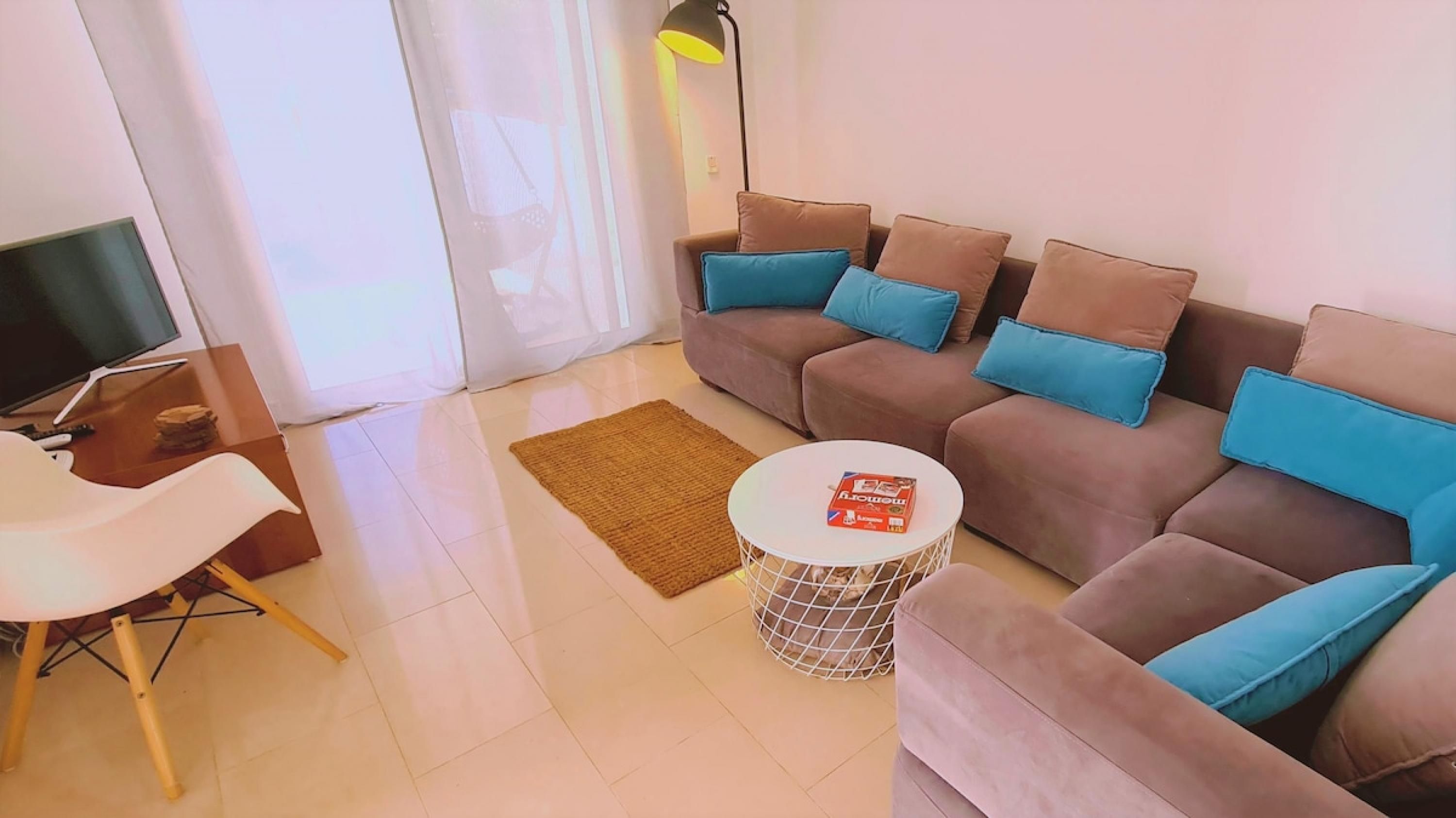 A living room with a sofa set, a coffee table, a TV, and a lamp.