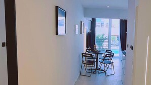 Ein schmaler Flur führt zu einem Essbereich mit Tisch und Stühlen, einem gerahmten Bild an der Wand und Blick durch eine Glastür nach draußen.