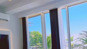A hotel room with a bed, a TV, and large windows with curtains. - 116 AN 1 - Mezarina 1 Apartment (Ayia Napa)