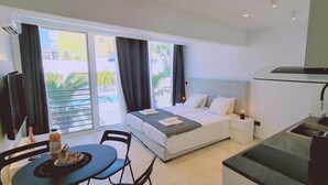 A hotel room with a bed, a desk, a chair, a table with breakfast items, and a view of the outside. - 116 AN 1 - Mezarina 1 Apartment (Ayia Napa)