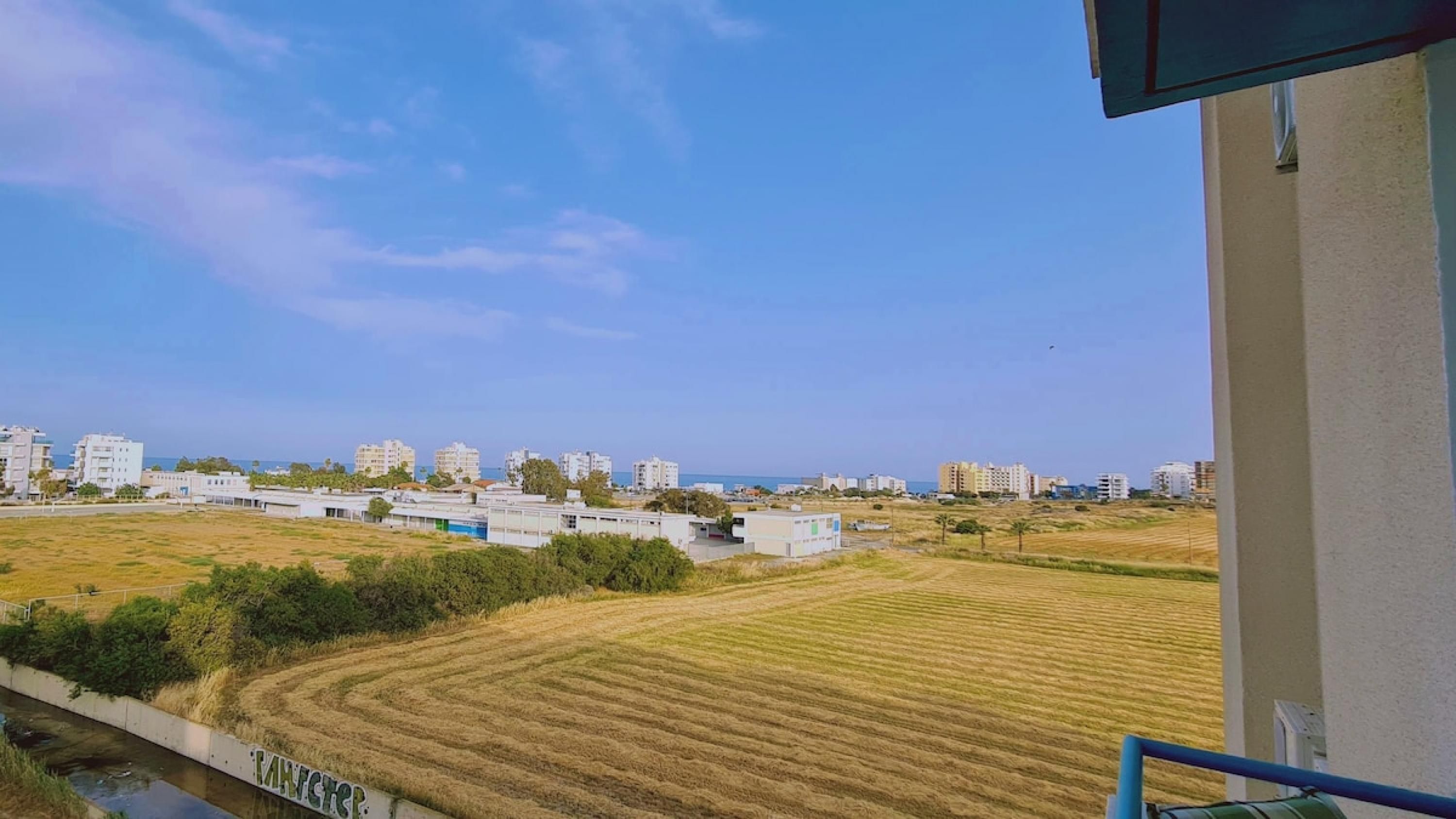 Vista di una zona costiera con edifici, un prato e una distesa d'acqua.
