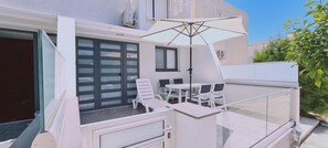 A balcony with a table, chairs, and an umbrella. - 14 AN - 113 Nissi Twins Apartment (Ayia Napa)