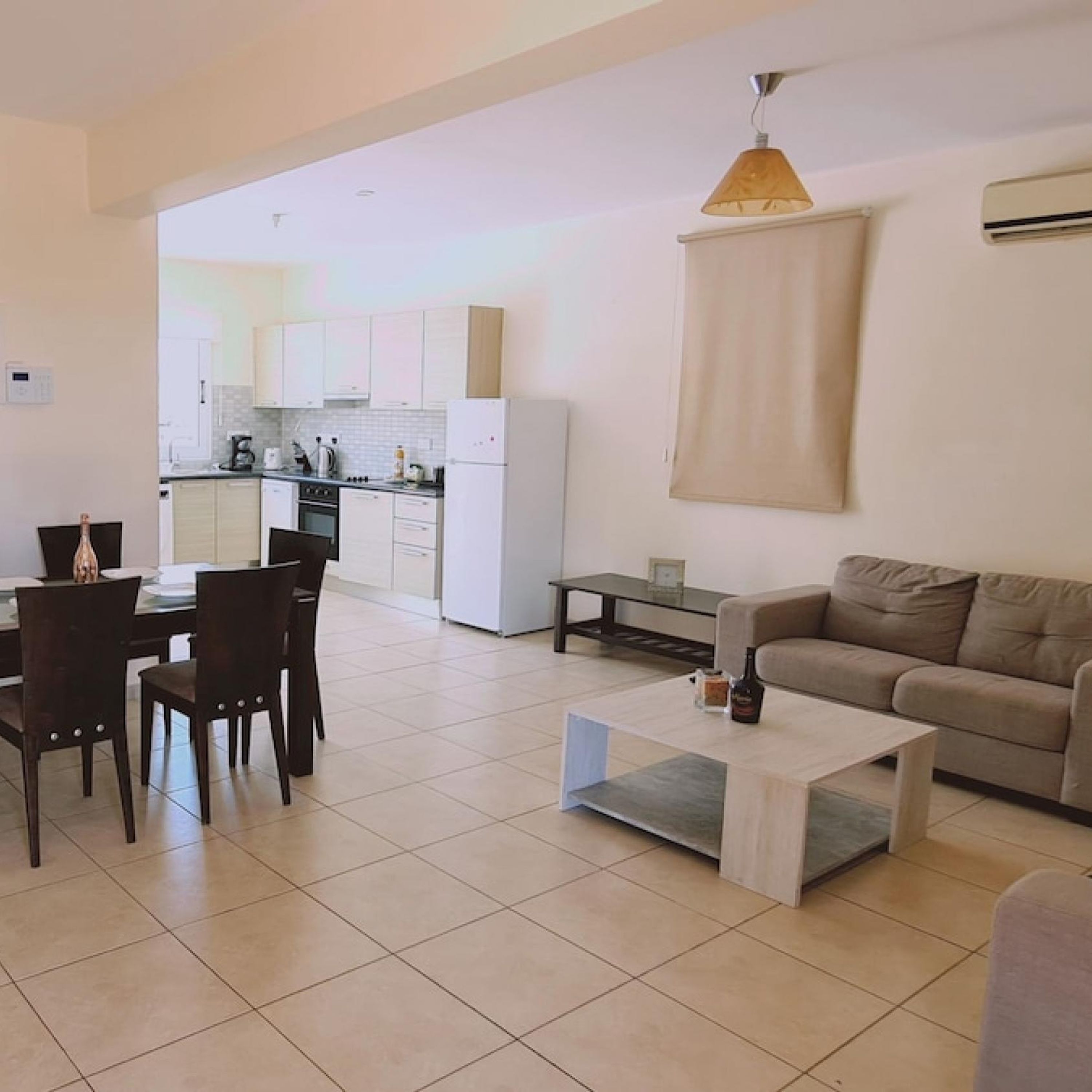 A modern living room with a sofa, coffee table, and dining area.