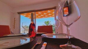 A dining table set with plates, cutlery, and a wine bottle, with a view of a balcony and outdoor umbrellas. - 42 PRO -stay Symphony Apartment (Paralimni)