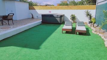 Relax in an outdoor space with a lawn, lounge chairs, and a hot tub.
