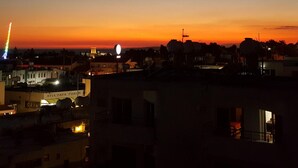 A cityscape at dusk with buildings silhouetted against a sunset sky.