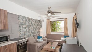 A compact living space with a kitchenette, a sofa, a dining table, and a ceiling fan.