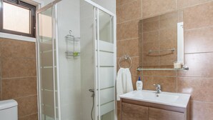 A bathroom with a glass-enclosed shower, a white sink, and a wooden vanity.