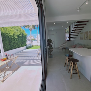 A modern interior with a kitchen area, dining space, and a view of the outdoors. - Stay Sunshine Aura in Protaras (Paralimni)