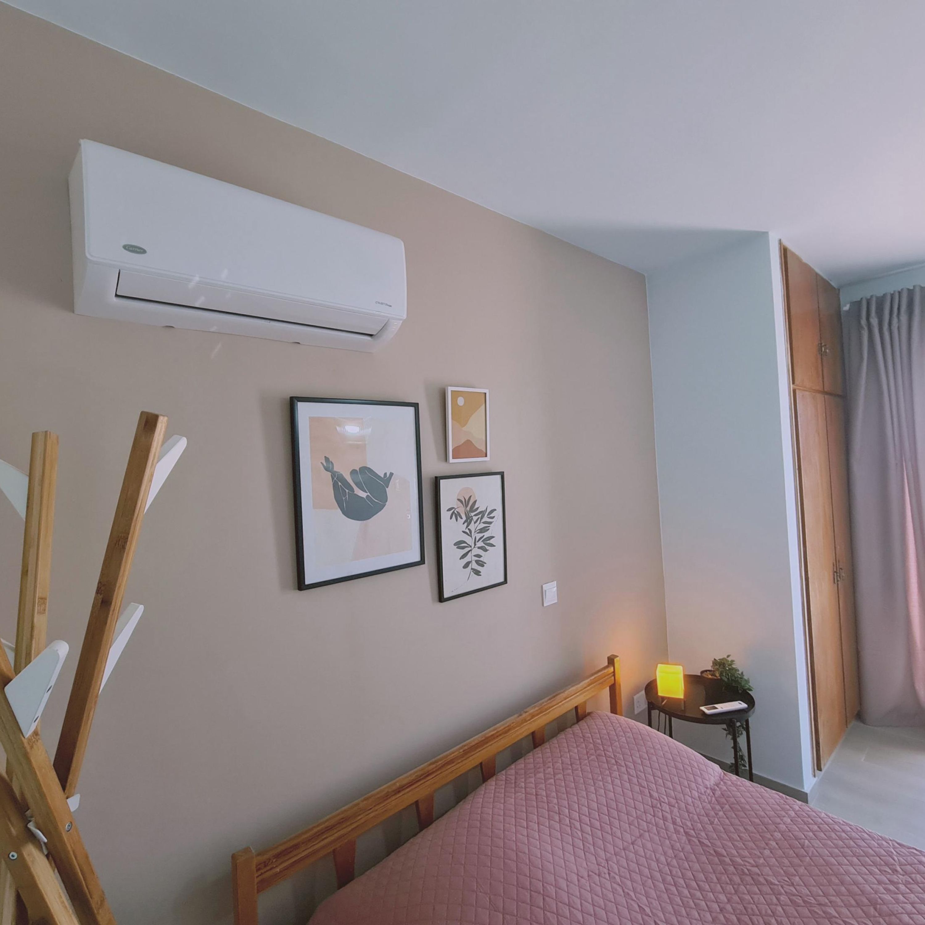 Une chambre à coucher avec un lit, un climatiseur et deux tableaux encadrés accrochés au mur.