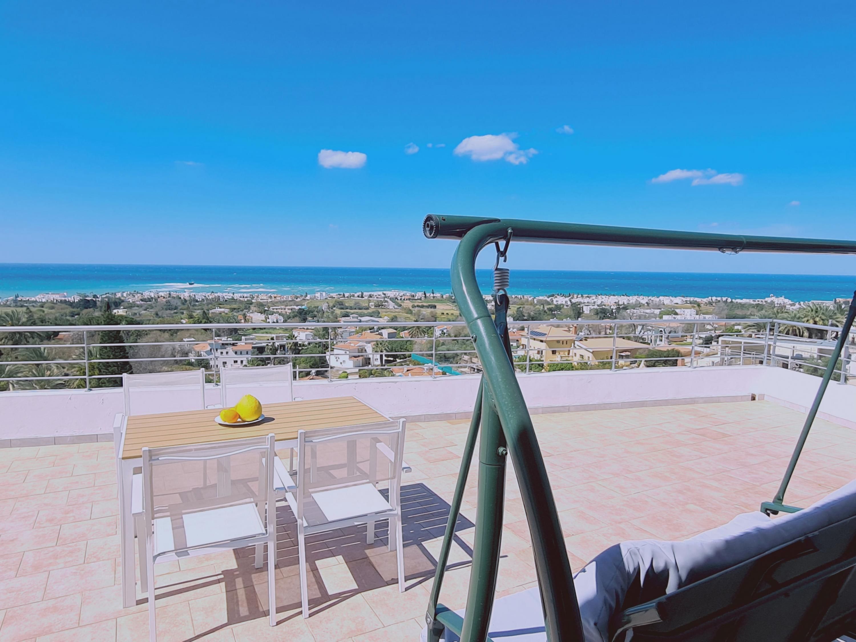 En terrass med ett bord och stolar, med utsikt över en kuststad.