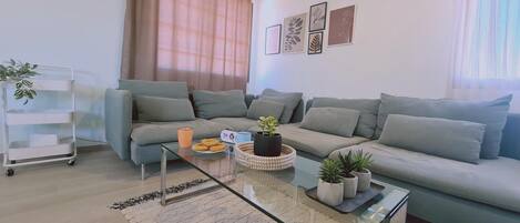A modern living room with a sectional sofa, a glass coffee table, and a small plant on the table.