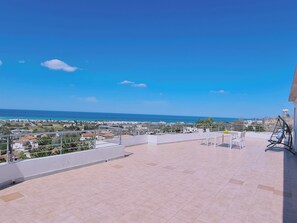 Une terrasse sur le toit offrant une vue sur la mer et les bâtiments environnants.