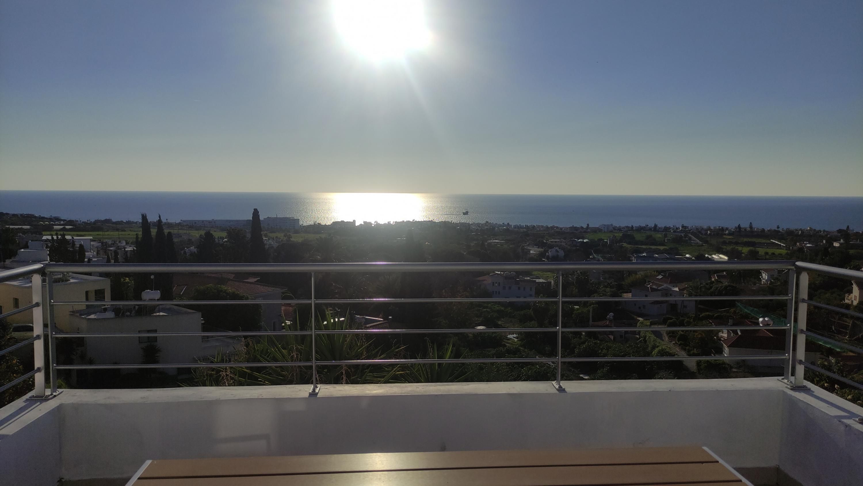 A balcony with a view of the sea and a sunset.