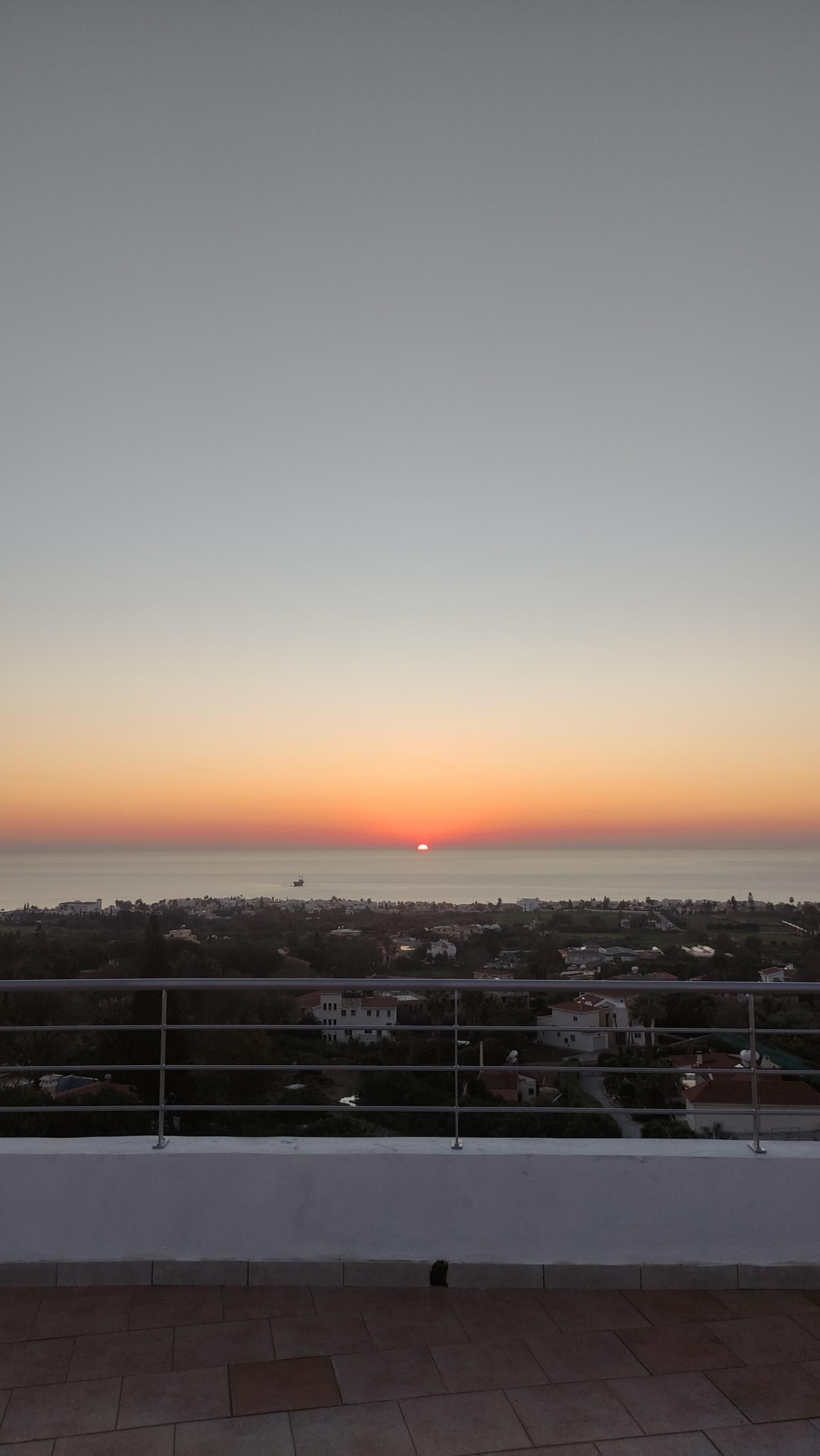 A sunset view from a balcony overlooking a coastal town.