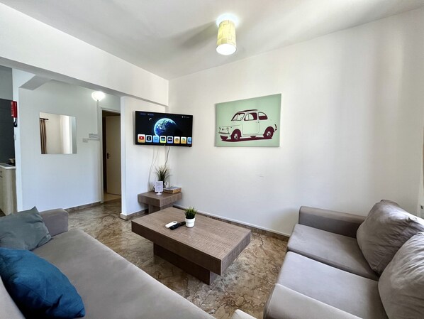 A modern living room with a flat-screen TV, a coffee table, and a sofa. - 00 HA - HA DE CO A in Ayia Napa (Ayia Napa)
