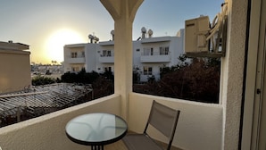 A balcony with a glass table and chairs, overlooking a residential area with buildings and a clear sky. - 00 HA - HA DE CO C in Ayia Napa (Ayia Napa)