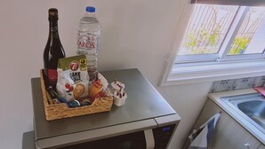 A kitchen counter with a bottle of wine, a water bottle, a basket of baked goods, and a small figurine. - 00 HA - HA DE CO C in Ayia Napa (Ayia Napa)
