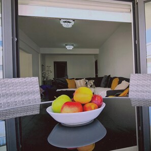 Een fruitschaal op een tafel in een moderne woonkamer met een bank en kussens.