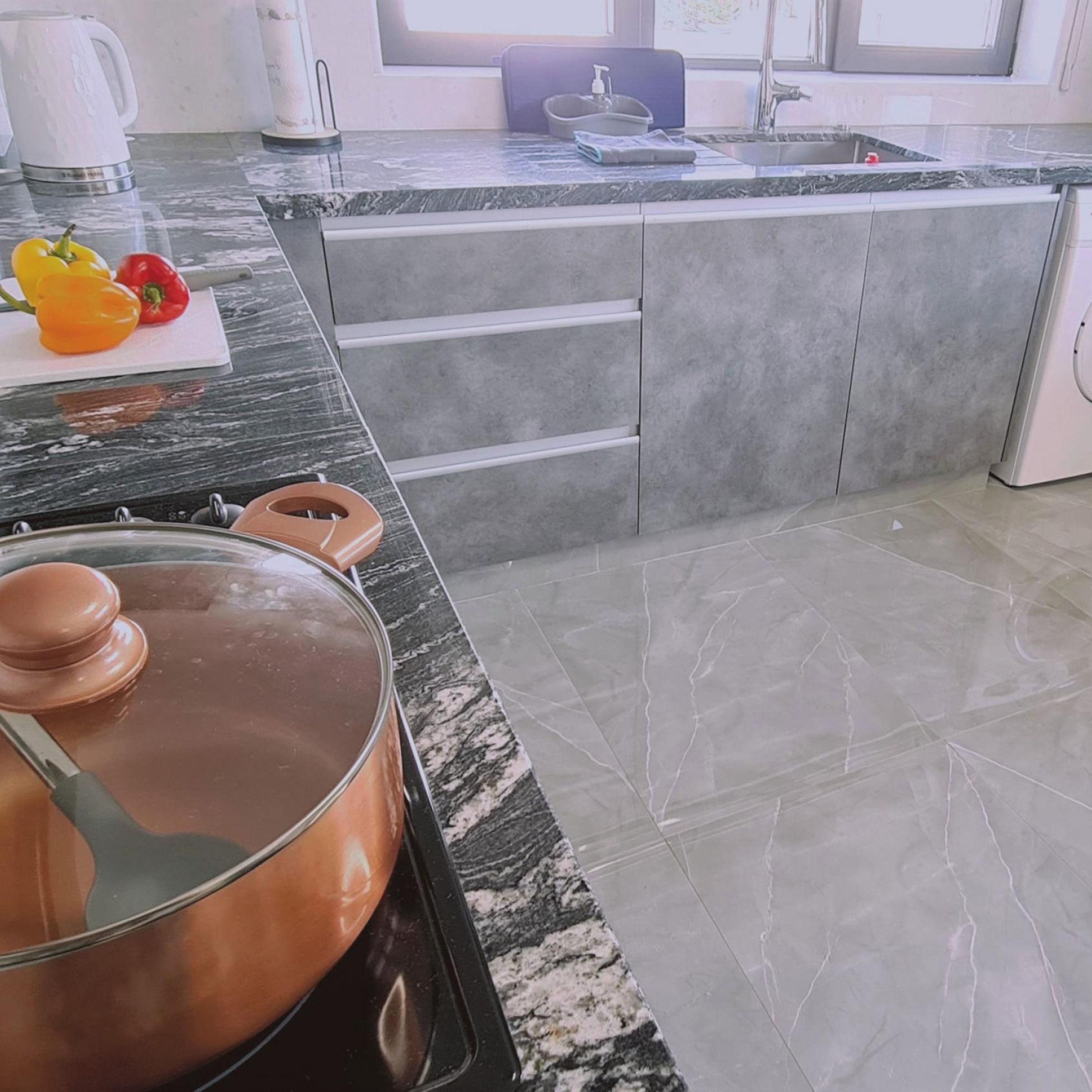 A kitchen with a granite countertop, a stove, and a sink.