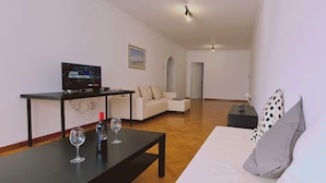 Ein modernes Wohnzimmer mit einer Couch, einem Couchtisch und einem Fernseher, der eine Werbung zeigt.