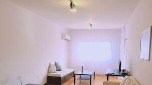 Ein minimalistisch eingerichtetes Wohnzimmer mit einer Couch, einem Couchtisch und einem TV-Schrank.
