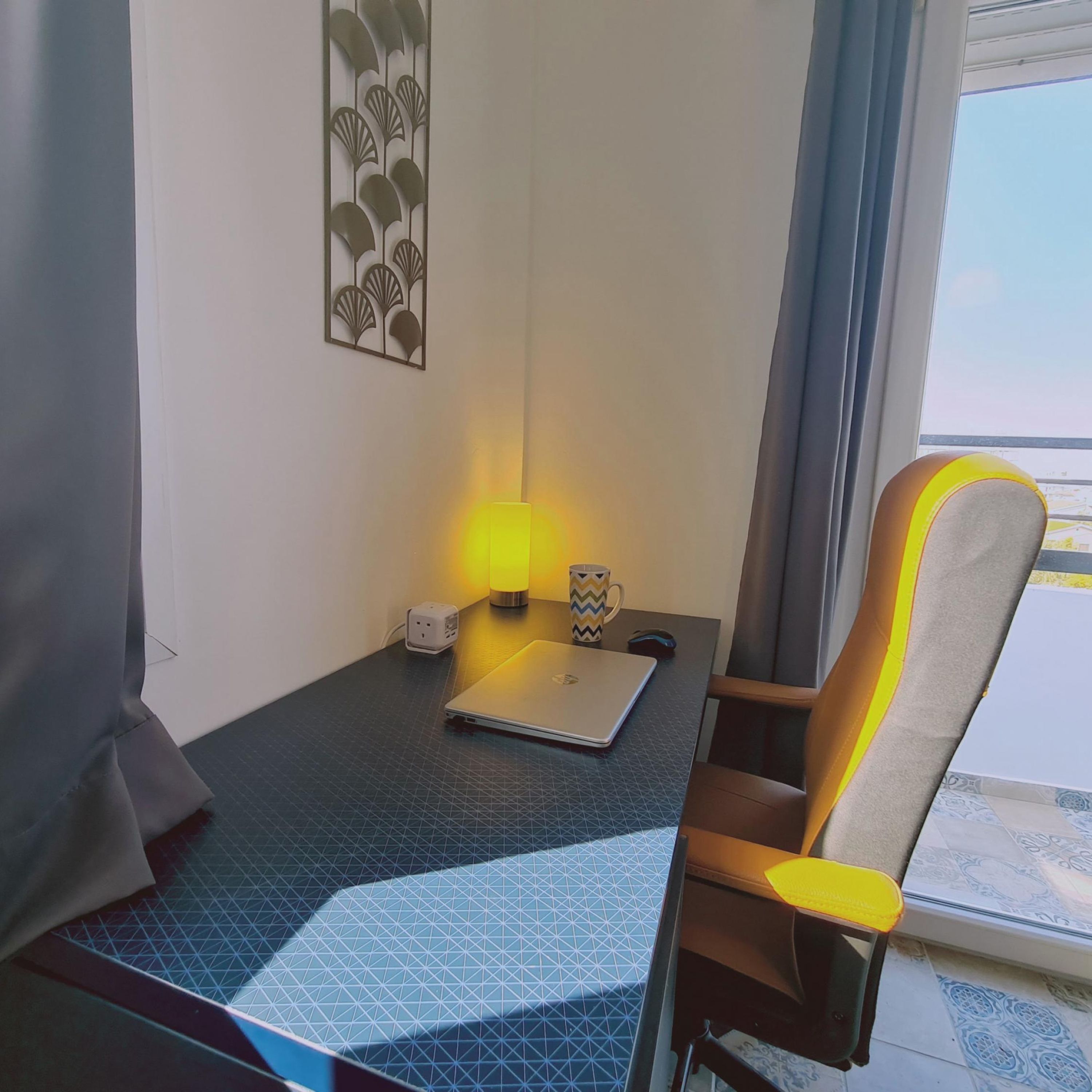 A hotel room with a desk, a laptop, a lamp, and a chair.