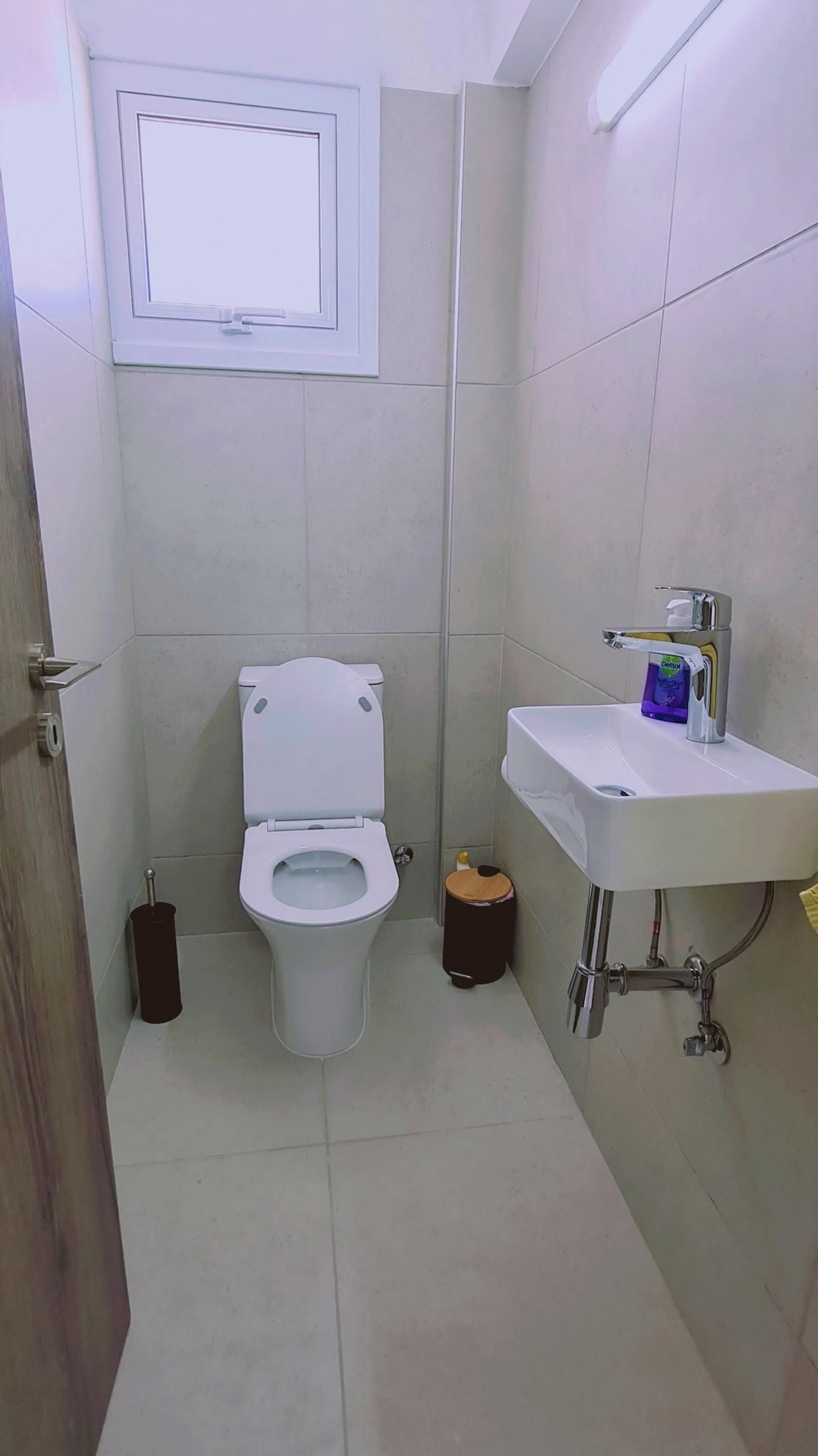 Ein kleines Badezimmer mit Toilette, Waschbecken und Fenster.