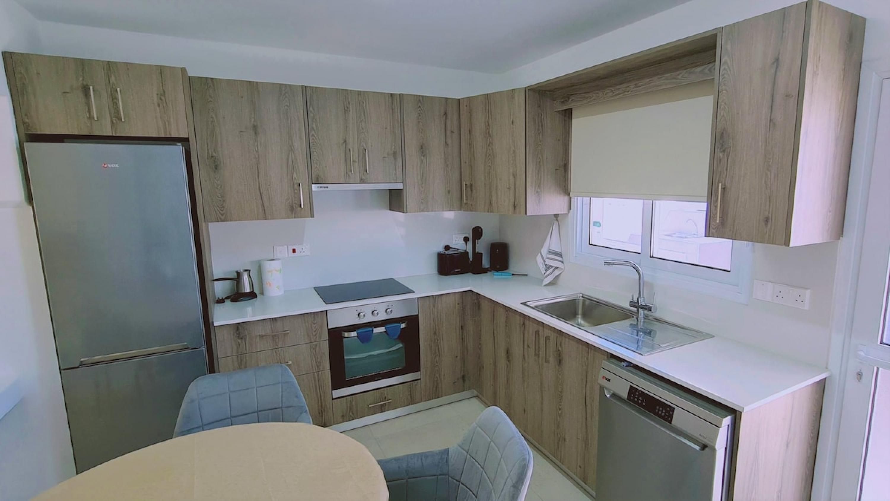 A compact kitchen with wooden cabinets, a refrigerator, a stove, a sink, and a dishwasher.