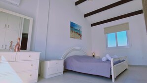 A bedroom with a bed, a dresser, a mirror, a painting, and a window. - 48 PER - Mellissa Villa (Paralimni)