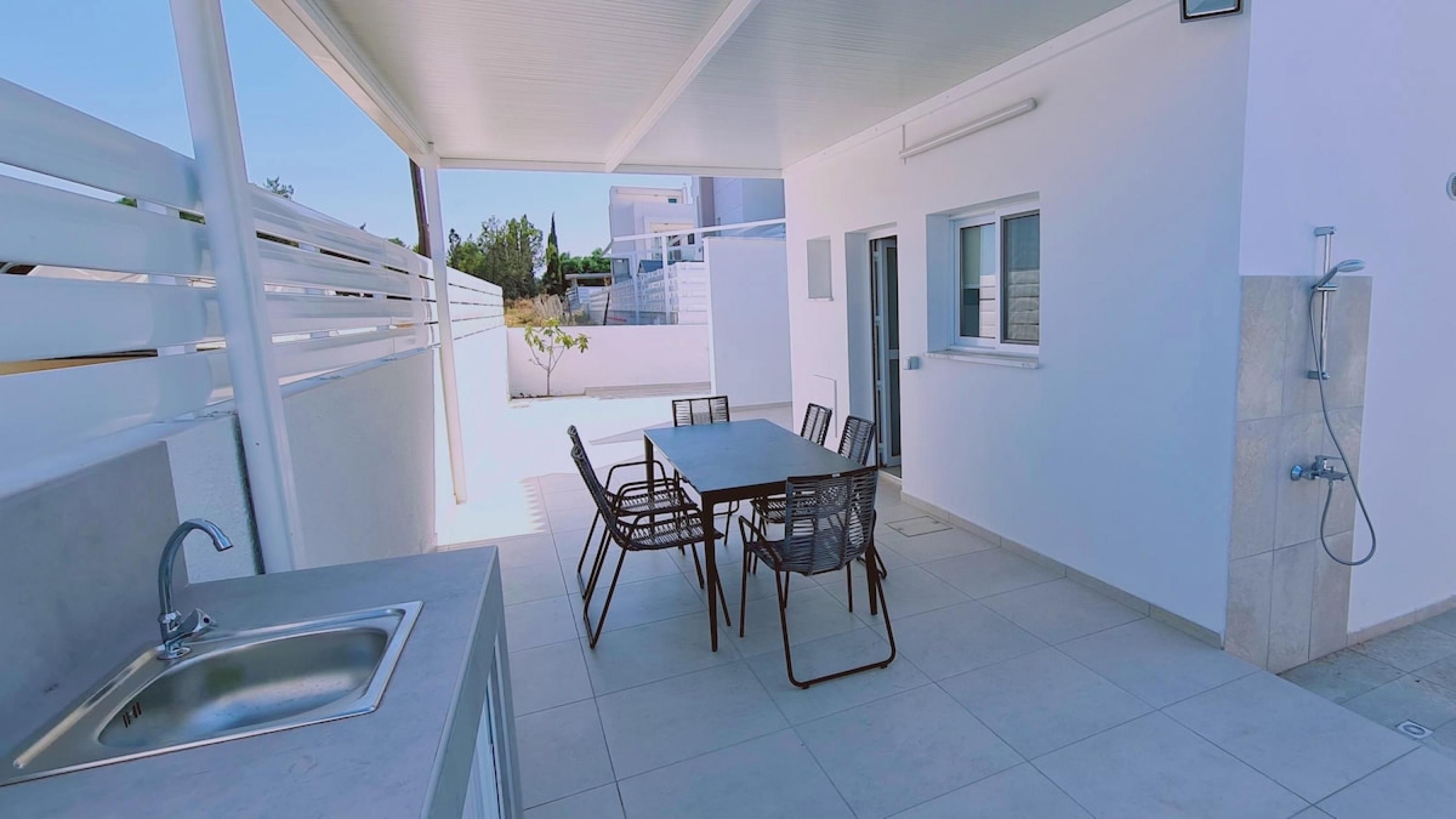 A patio with a table and chairs, a sink, and a shower.