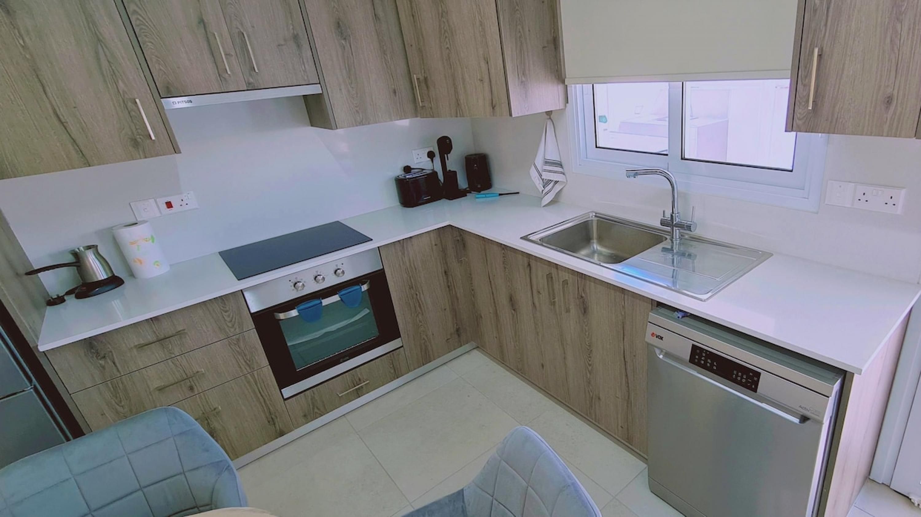 A modern kitchen with a built-in oven, dishwasher, and a double sink.