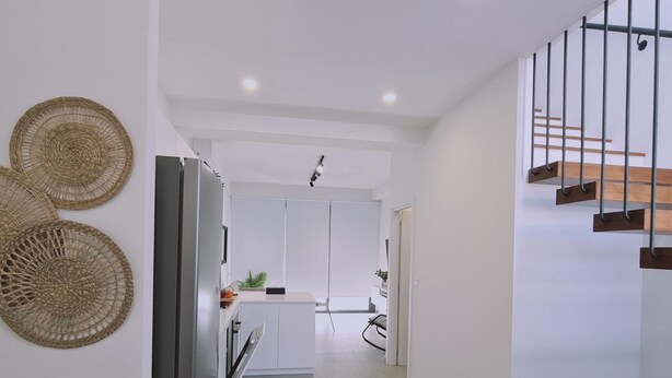 Eine moderne Küche mit Kochinsel, Kühlschrank und einer Treppe mit Holzbodenstufen.