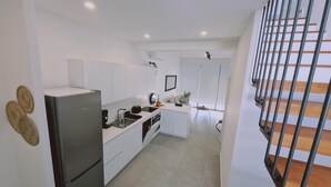 Eine moderne Küche mit weißen Schränken, einem Bosch-Kühlschrank und einem kleinen Essbereich mit Tisch und Stühlen.