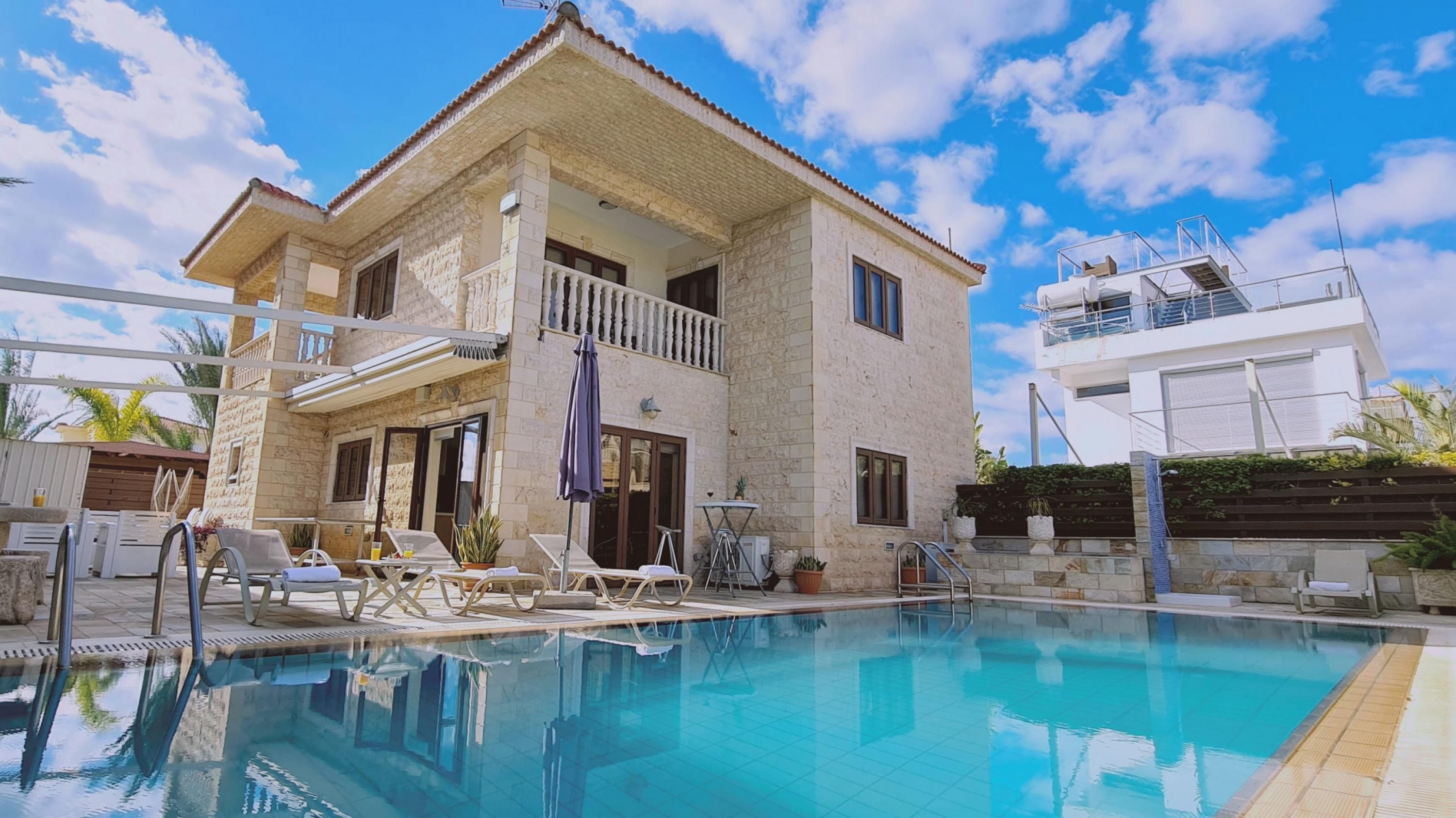 A two-story building with a swimming pool, a balcony, and a modern extension.